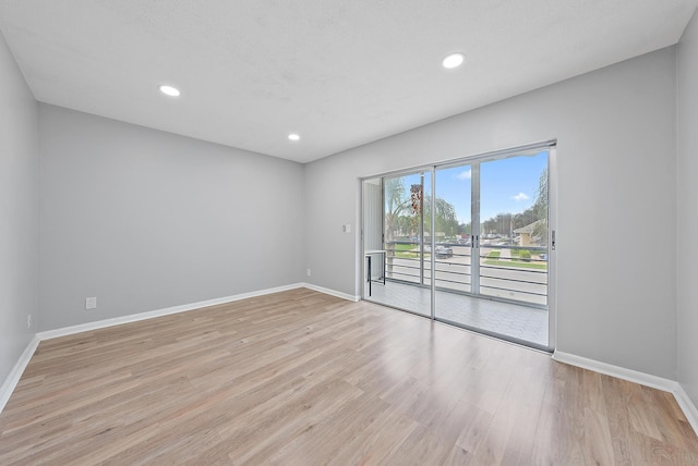 empty room with light wood finished floors, recessed lighting, and baseboards