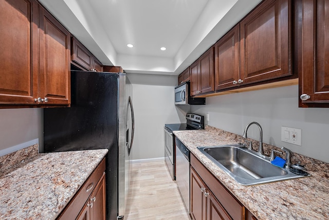 kitchen featuring recessed lighting, a sink, stainless steel appliances, light wood-style flooring, and baseboards