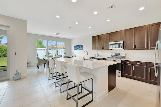 kitchen featuring light tile patterned floors, sink, a kitchen island with sink, appliances with stainless steel finishes, and a breakfast bar area