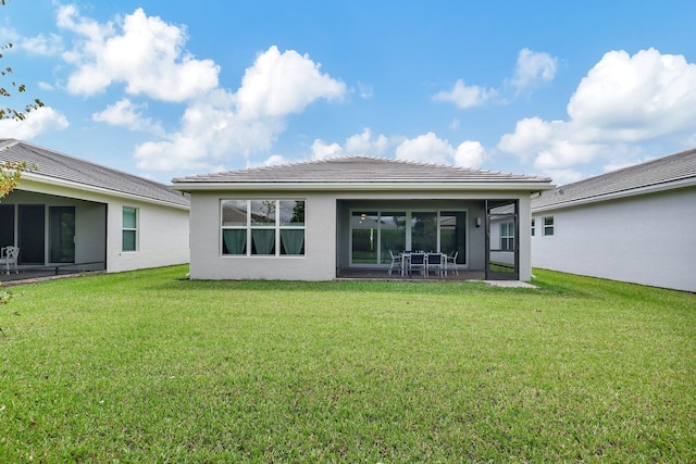 rear view of house featuring a lawn and a patio