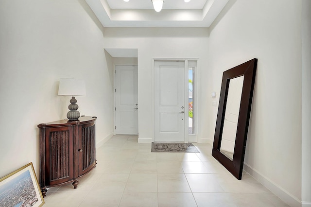 tiled foyer featuring a high ceiling and a tray ceiling