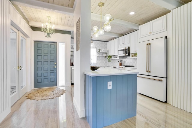 kitchen featuring stainless steel microwave, light countertops, white cabinetry, pendant lighting, and built in fridge