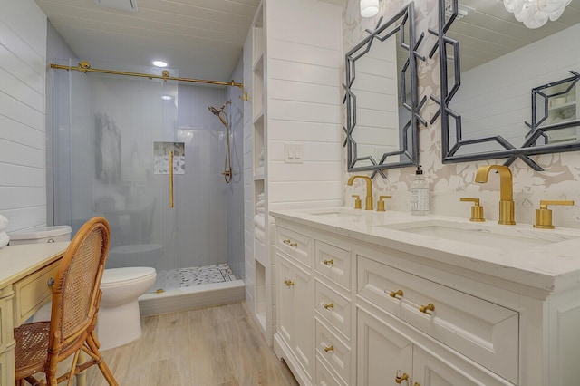 full bathroom with a stall shower, double vanity, a sink, and wood finished floors