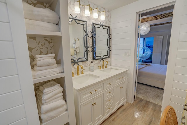 ensuite bathroom with double vanity, ensuite bathroom, a sink, and wood finished floors