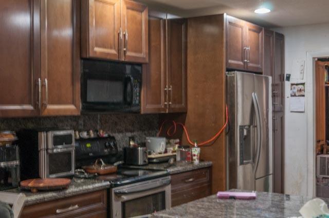 kitchen featuring decorative backsplash, dark stone countertops, dark brown cabinets, and sink