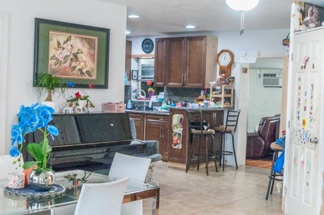 kitchen with decorative backsplash, an AC wall unit, sink, and light tile patterned floors