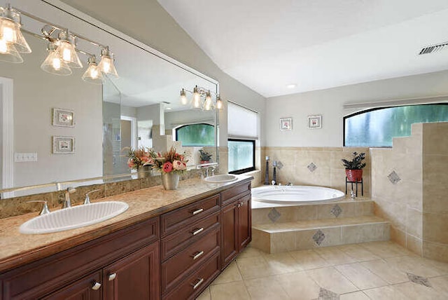 bathroom featuring a wealth of natural light, tile patterned floors, tiled tub, and vanity