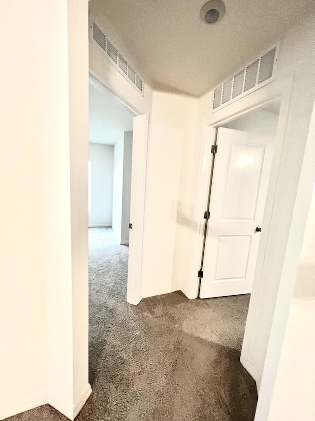 hall featuring dark carpet and a textured ceiling