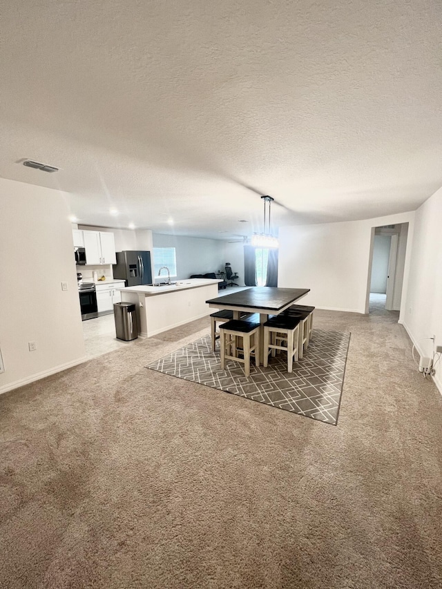 dining room with baseboards, visible vents, a textured ceiling, and light colored carpet