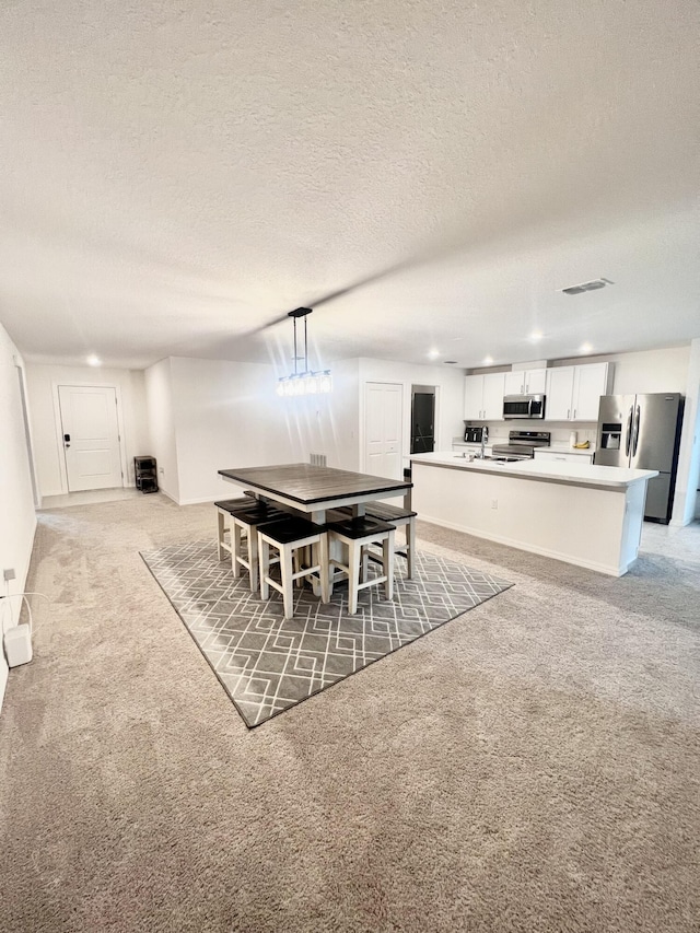 dining room featuring light carpet, recessed lighting, a textured ceiling, and visible vents