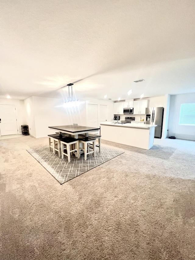 dining space featuring a textured ceiling and light colored carpet