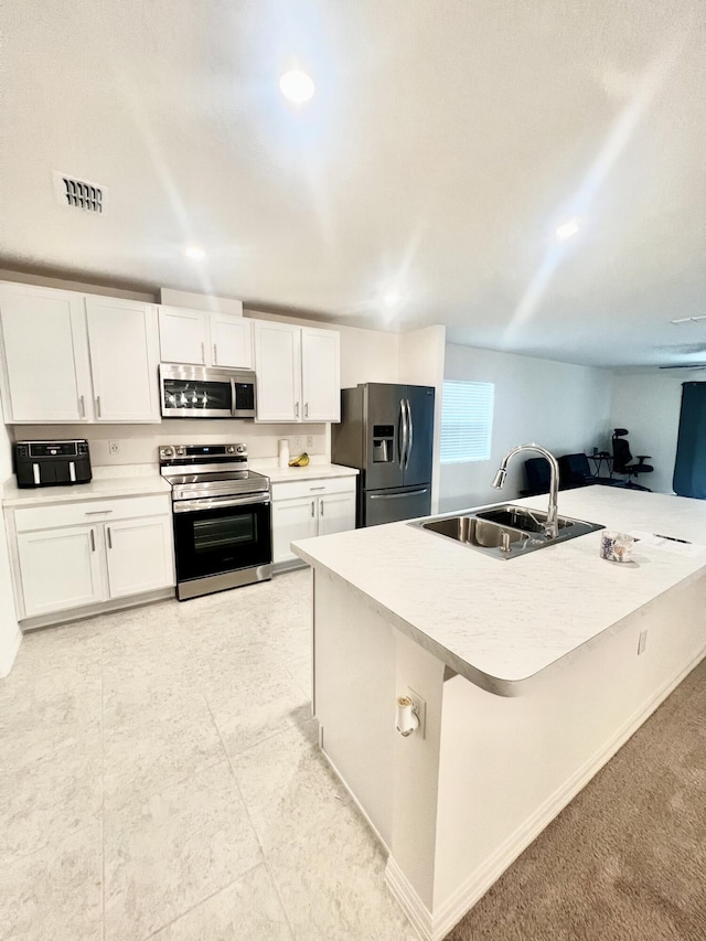 kitchen featuring white cabinets, sink, kitchen peninsula, appliances with stainless steel finishes, and a breakfast bar area