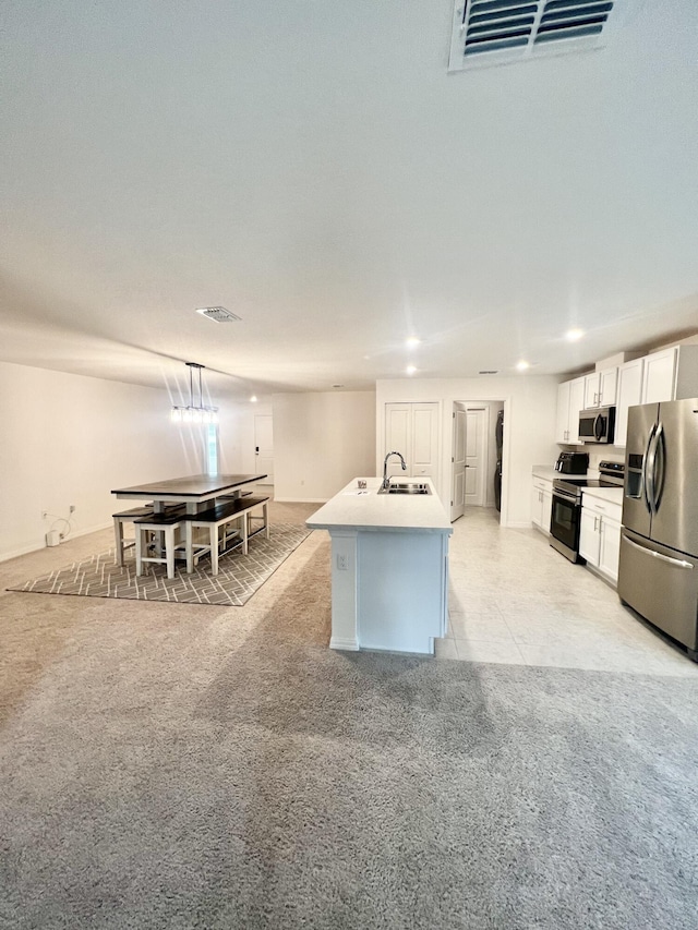 kitchen with sink, an island with sink, white cabinetry, light colored carpet, and appliances with stainless steel finishes