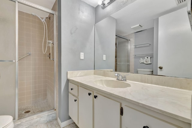 bathroom featuring toilet, vanity, and a shower with door