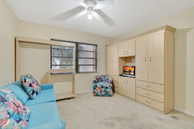 sitting room with ceiling fan, a textured ceiling, and light carpet