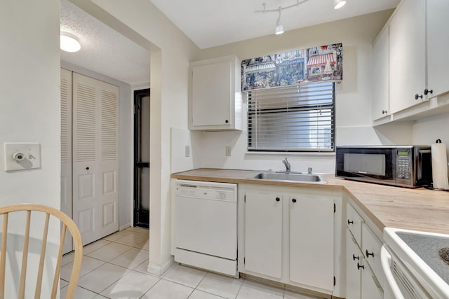 kitchen with sink, white dishwasher, a textured ceiling, light tile patterned floors, and white cabinets