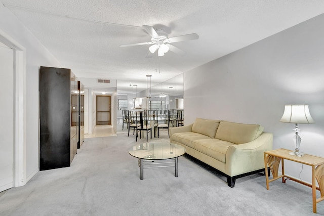 living room featuring a textured ceiling, light carpet, and ceiling fan