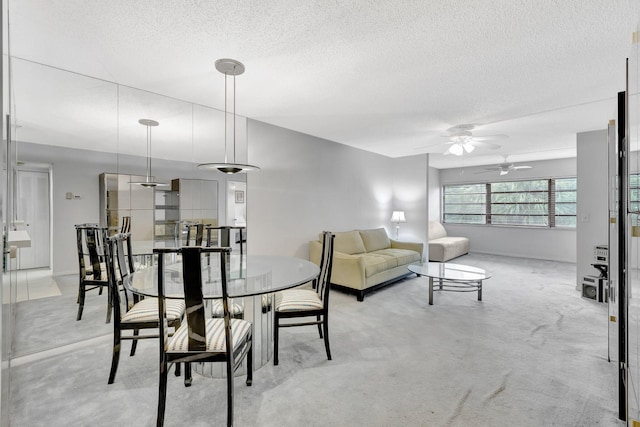 carpeted dining room with a textured ceiling and ceiling fan