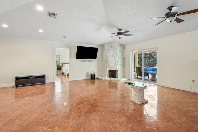 unfurnished living room featuring ceiling fan, a stone fireplace, and a textured ceiling