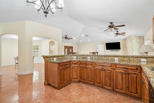 kitchen featuring a chandelier, light stone countertops, a textured ceiling, and vaulted ceiling