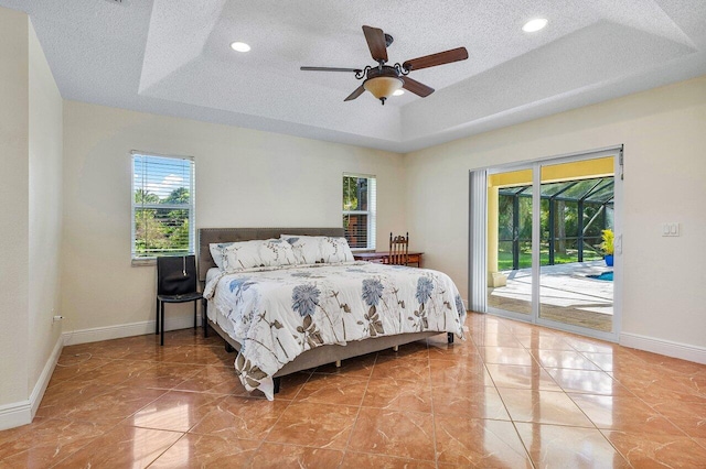 bedroom featuring access to outside, a textured ceiling, a raised ceiling, and ceiling fan