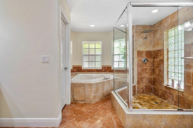 bathroom with a textured ceiling, independent shower and bath, and a wealth of natural light