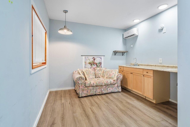 sitting room with an AC wall unit, sink, and light wood-type flooring