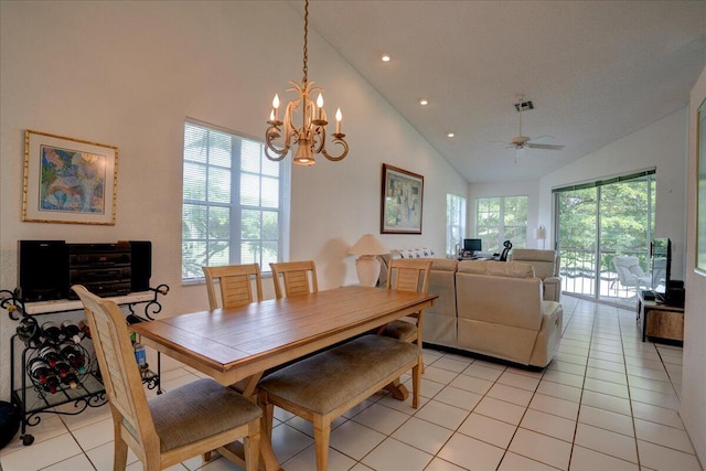 tiled dining area with ceiling fan with notable chandelier, high vaulted ceiling, and a healthy amount of sunlight