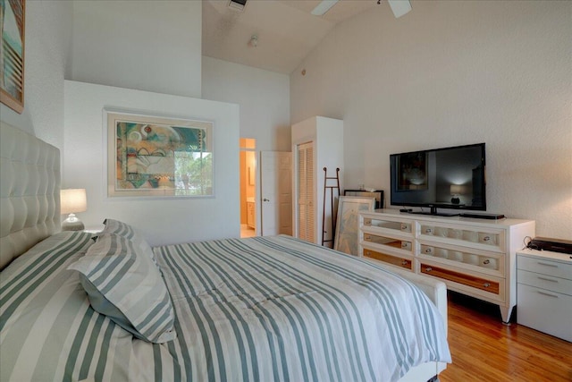 bedroom featuring ceiling fan, light hardwood / wood-style flooring, a closet, and high vaulted ceiling