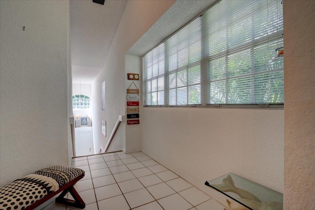 corridor with light tile patterned flooring and a healthy amount of sunlight