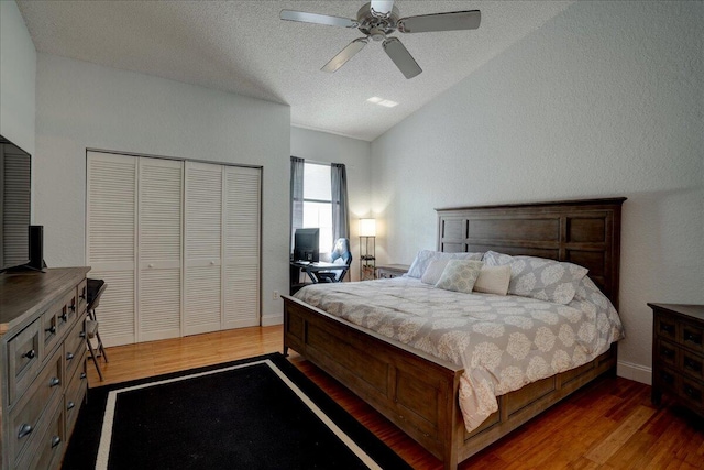 bedroom with vaulted ceiling, a closet, a textured ceiling, ceiling fan, and dark hardwood / wood-style floors