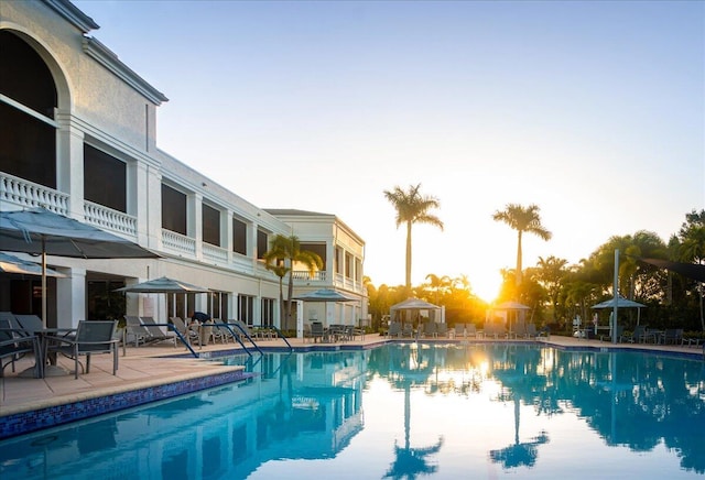 pool at dusk featuring a gazebo and a patio