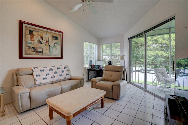 living room featuring vaulted ceiling, ceiling fan, light tile patterned floors, and a textured ceiling