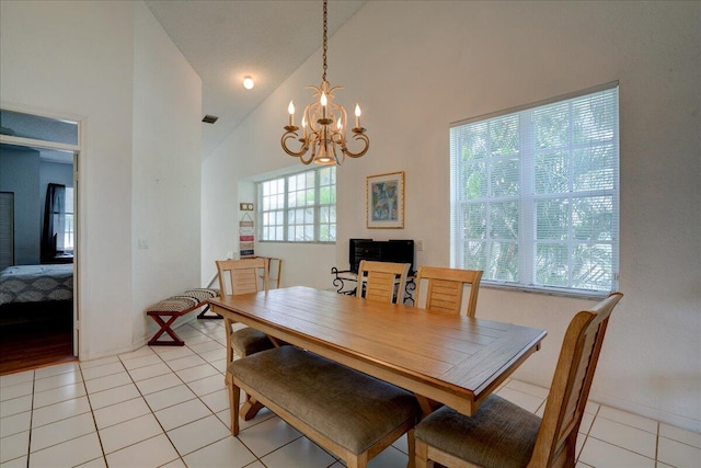 dining area with high vaulted ceiling, light tile patterned floors, and an inviting chandelier