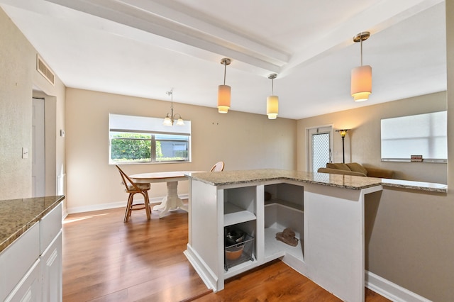 kitchen featuring hanging light fixtures, hardwood / wood-style floors, light stone counters, and white cabinets