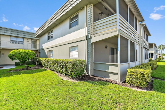 view of home's exterior with a balcony and a lawn