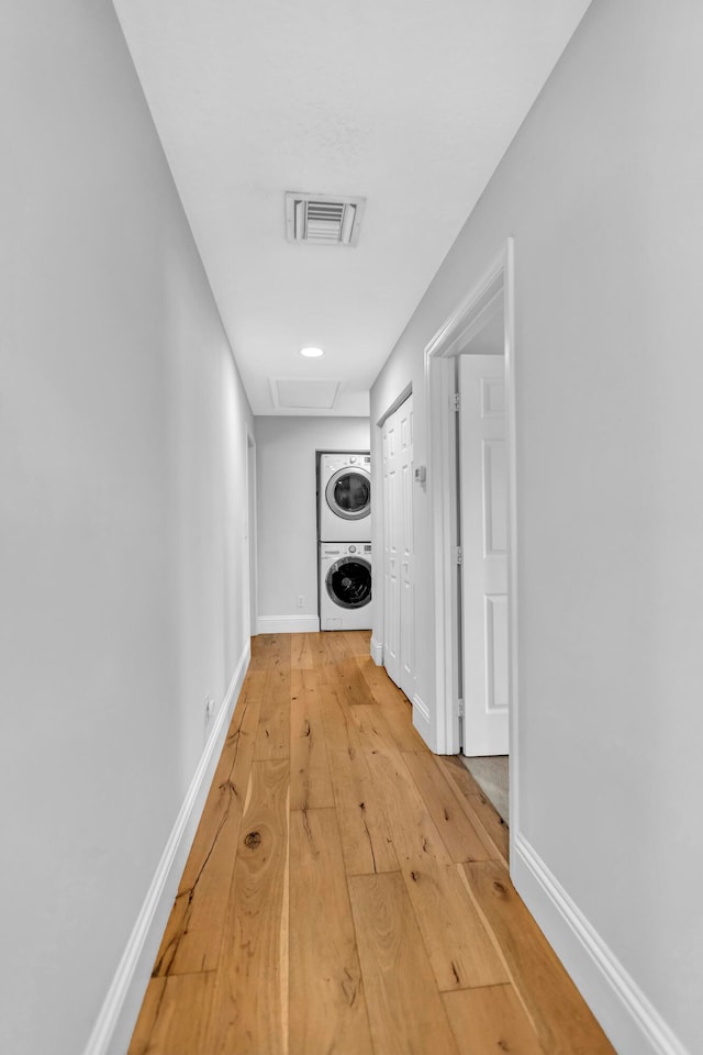 hallway with hardwood / wood-style flooring and stacked washer / drying machine