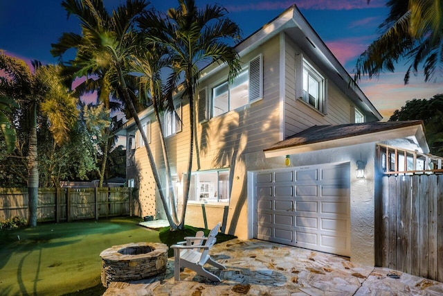 property exterior at dusk with a garage and a fire pit