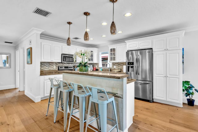 kitchen with a center island, stainless steel appliances, white cabinetry, a kitchen bar, and light hardwood / wood-style flooring