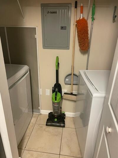 washroom featuring washing machine and clothes dryer, electric panel, and light tile patterned floors