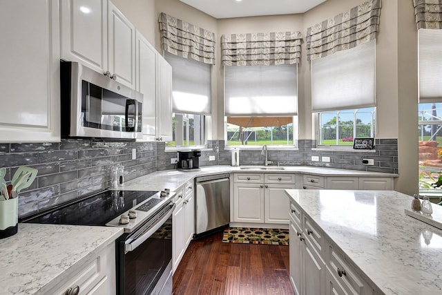 kitchen with white cabinets, backsplash, appliances with stainless steel finishes, dark hardwood / wood-style flooring, and sink