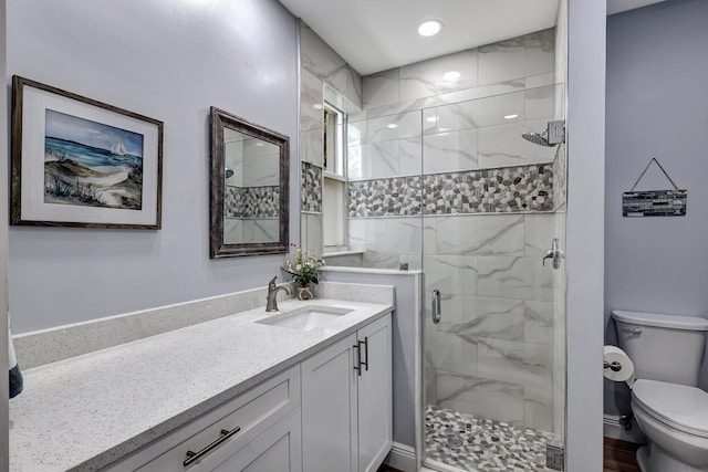 bathroom featuring vanity, a shower with shower door, and toilet