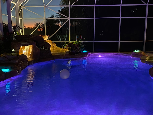 pool at dusk with pool water feature and glass enclosure