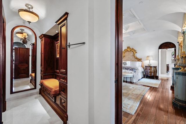 corridor featuring beam ceiling, light hardwood / wood-style floors, and coffered ceiling