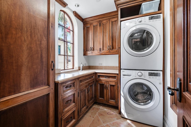 laundry room featuring sink, cabinets, and stacked washer and clothes dryer