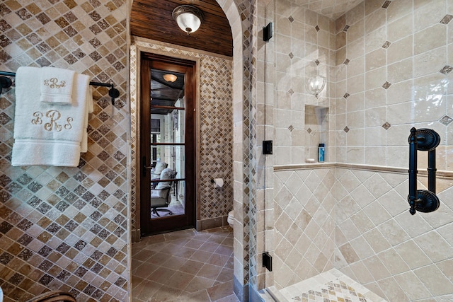 bathroom with tile patterned flooring, a shower with door, and tile walls