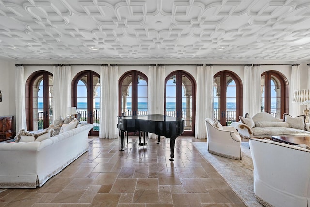 living room with french doors, a water view, and a healthy amount of sunlight