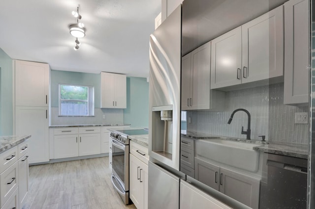 kitchen featuring decorative backsplash, stainless steel electric range, white cabinets, light stone countertops, and light wood-type flooring