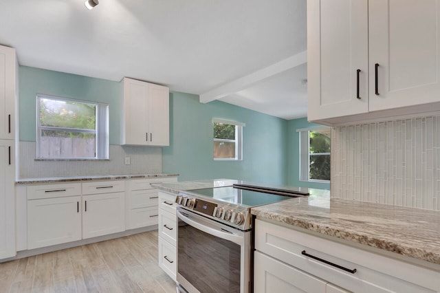 kitchen with stainless steel range with electric stovetop, white cabinetry, decorative backsplash, and a wealth of natural light