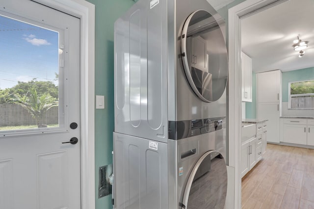 laundry area featuring stacked washer / drying machine and light hardwood / wood-style floors